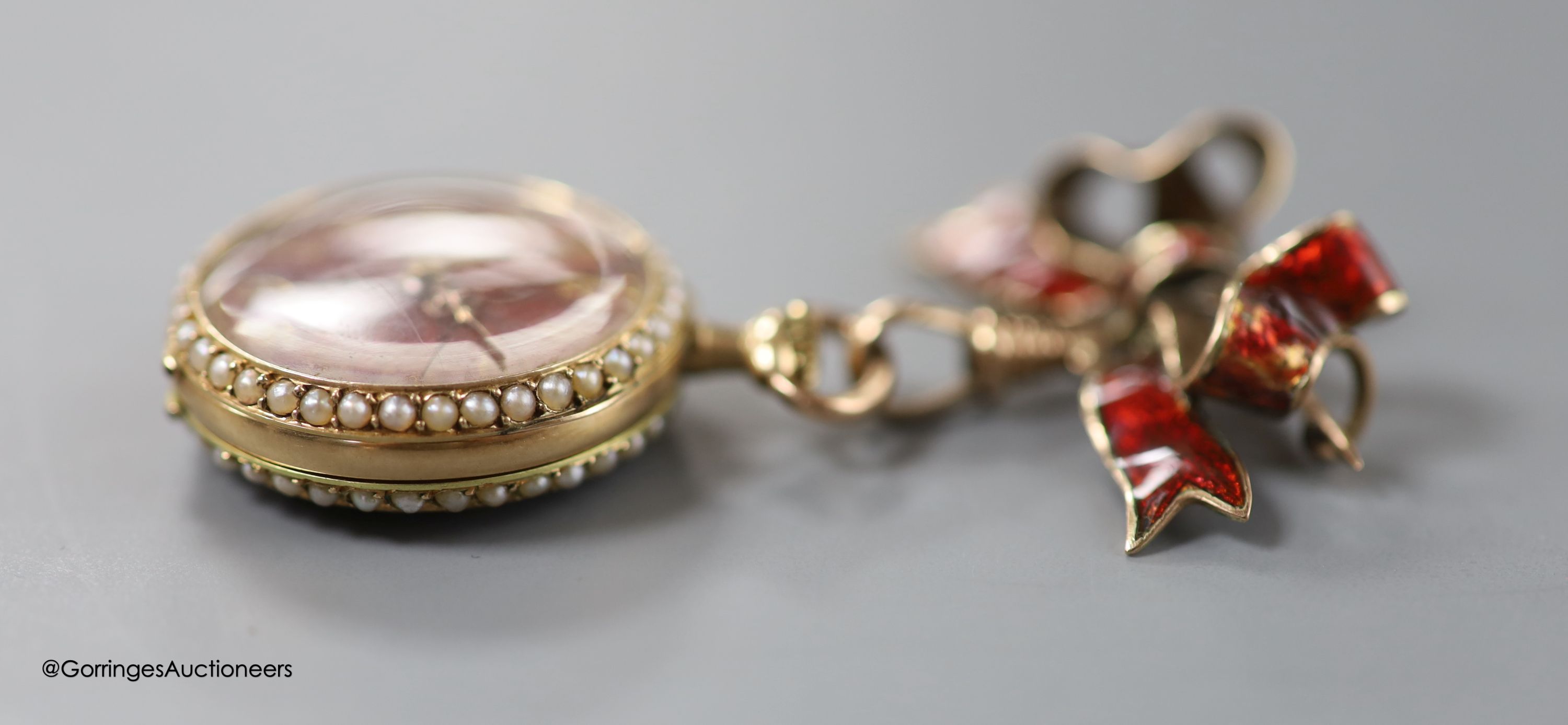 A lady's early 20th century 14k yellow metal, red enamel and seed pearl set fob watch(a.f.), case diameter 26mm, gross 15.5 grams, on a 9ct and red enamel bow brooch, gross 4.6 grams.